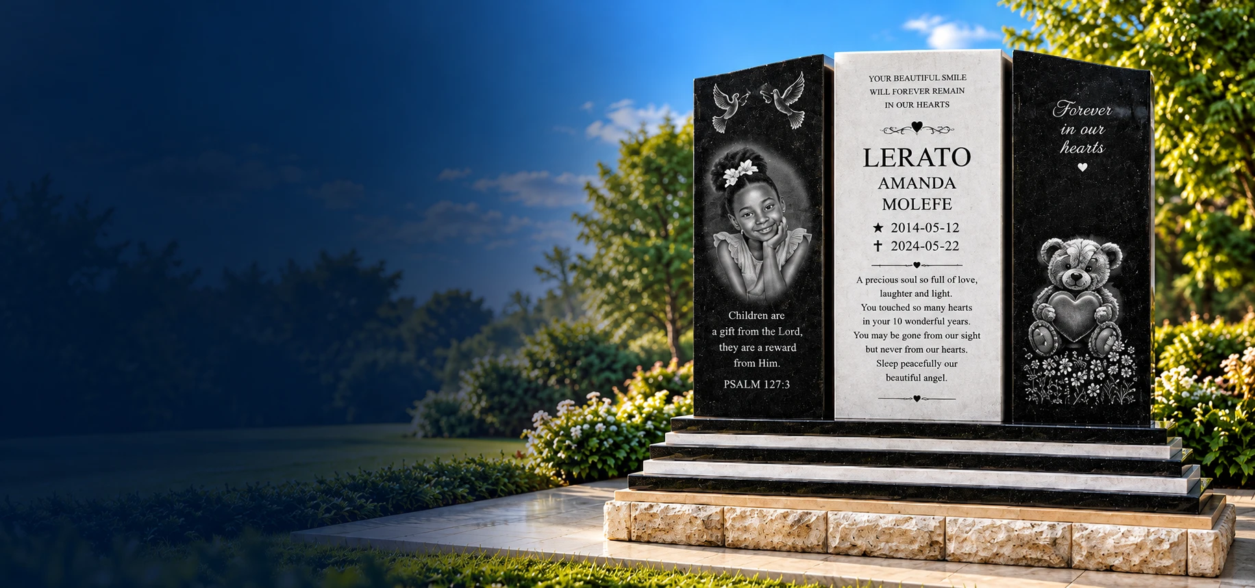 A black and white granite memorial with a portrait and teddy bear engraving, in a sunny garden